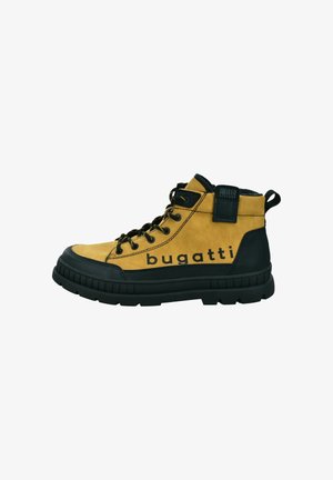Gelbe Wildleder-Wanderschuhe mit schwarzer Gummisohle und Akzenten, ausgestattet mit schwarzen Schnürsenkeln und einem Logodetail an der Seite. Eingelassene Nähte sichtbar.