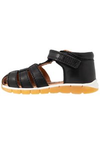 Černá kožená sandál s otevřeným designem, vyznačující se křížovými popruhy, nastavitelným uzavřením na suchý zip a žlutou gumovou podrážkou.