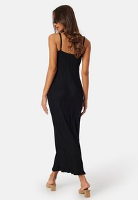 Abito lungo nero a costine con spalline sottili, silhouette adatta e orlo dritto, realizzato in tessuto morbido e leggero con una texture sottile.