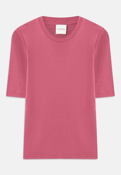 Rövid ujjú póló puha, rózsaszín pamutból, kerek nyakkivágással. A szegélyeken varrási részletekkel és egyenes szabással rendelkezik.