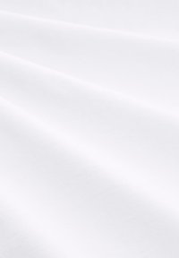 Λευκό ύφασμα με λεία, ματ υφή, που εμφανίζει διακριτικές πτυχώσεις και ζάρες, υποδηλώνοντας ελαφρύ και ευέλικτο υλικό κατάλληλο για διάφορες χρήσεις.