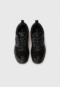 Black athletic shoes with a mix of suede and mesh materials, featuring textured accents, flat laces, and a rubber sole.