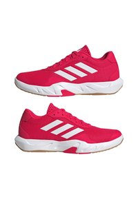 Felroze sportschoenen met een witte drie-strepen ontwerp, mesh bovenwerk, gevoerde zool en gumrubberen buitenzool. Laag uitgesneden silhouet.