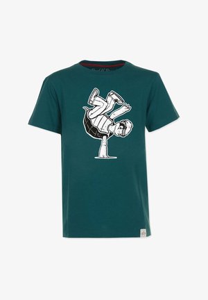 Teal bomuld t-shirt med et sort-hvidt grafik af en dreng, der balancerer på en skildpadde. Korte ærmer og rund hals design.