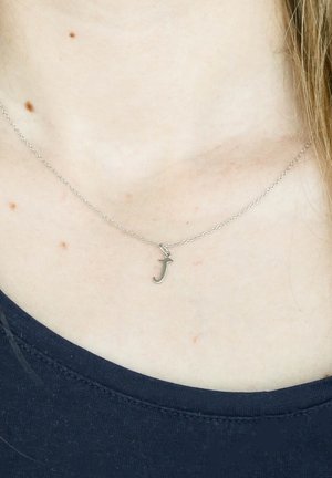 Zilveren ketting met een kleine "j" hanger, delicate ontwerp en gladde textuur, gedragen tegen een blote nek.