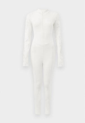Mute completo bianco con maniche lunghe, caratterizzato da dettagli testurizzati sulle braccia e una zip frontale. Design fluido e aderente.