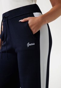 Navy joggingbroeken met witte zijstreep, van een katoenmix, met elastische tailleband, trekkoordsluiting en geborduurd "Guess" logo op de zak.