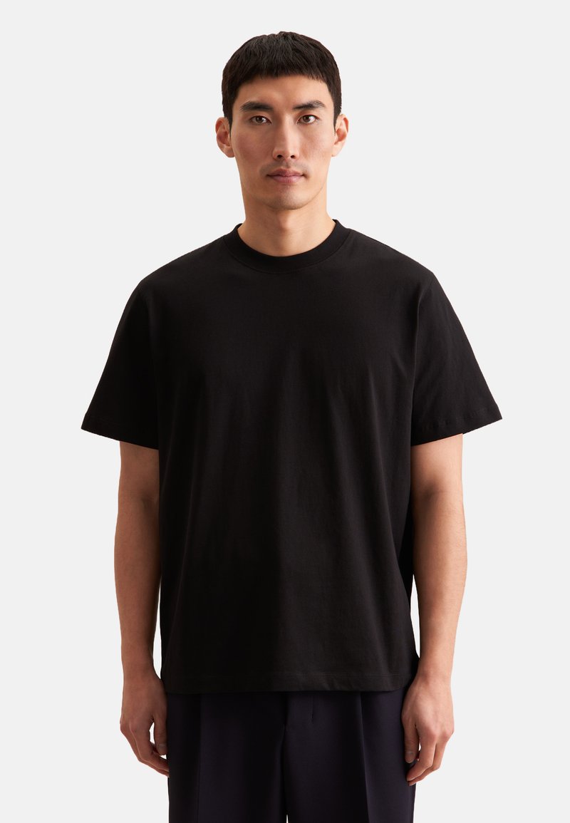 T-shirt nera in cotone con maniche corte, colletto girocollo e vestibilità comoda. Design minimalista, senza loghi o fantasie visibili.