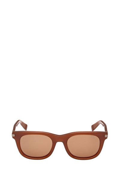 Ruskeat muoviset aurinkolasit, joissa on neliönmuotoiset kehykset, ruskeat linssit ja rakenteelliset ruskeat sankat, jotka on koristeltu metallisilla yksityiskohdilla.