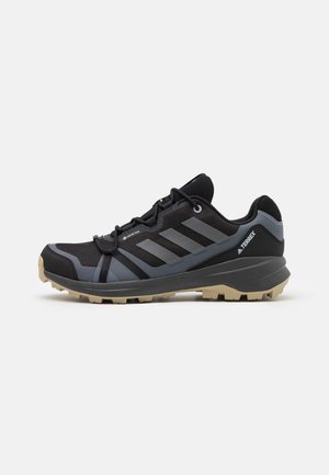 Chaussures de trail running légères noires avec accents gris, tige en mesh respirant, semelle extérieure robuste et système de laçage sécurisé.