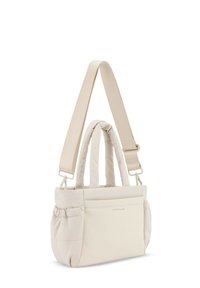 Beige pehmeä käsilaukku kahdella yläkahvalla ja säädettävällä olkahihnalla. Sisältää etutaskun ja hienovaraisen brändilogi. Suora pinta.