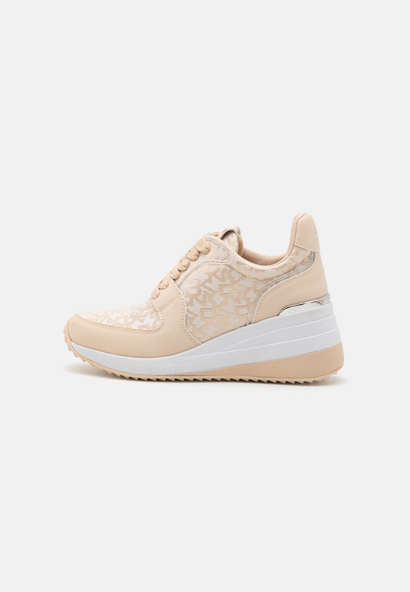 Beige színű sneaker, textúrált felsőrésszel, geometrikus mintával, fűzős záródással, és fehér platformtalpával, amelynek enyhe sarka van.