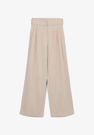 Pantalons larges beiges à taille haute, avec des plis à l'avant, une texture lisse et des coutures nettes, conçus pour une coupe décontractée.