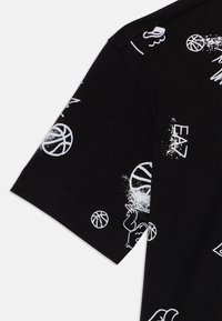Svart bomull T-skjorte med hvite grafiske basketballer og tegneserieaktige mønstre, med myk tekstur og korte ermer.