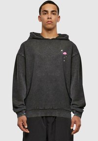 Sort oversized hættetrøje med en pink flamingo grafik på venstre bryst. Fremstillet af blødt, struktureret stof med snor i hætten og manchetter på ærmerne.