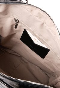 Zwarte leren handtas interieur met een gladde textuur, voorzien van een ritsvak en een pasjeshouder, tegen een beige voering.