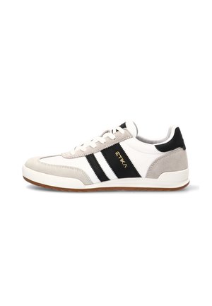 Zapatilla blanca y gris con rayas negras, logo "ETIKA", cordones blancos y suela marrón, vista desde el lado exterior.