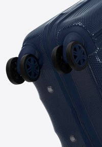 Hardshell koffer in marineblauw, met gestructureerd oppervlak, dubbele zwarte wielen en een centrale rits voor een veilige sluiting.