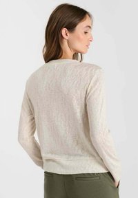 Hell-beige Pullover mit Rundhalsausschnitt, langen Ärmeln und einer weichen, strukturierten Oberfläche, das einen lässigen Schnitt und einen gerippten Saum hat.