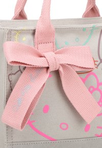 Borsa a tracolla grigia in tela con un accento in rosa a forma di fiocco intrecciato. Presenta stampe colorate e dettagli di cucitura, creando un design giocoso.