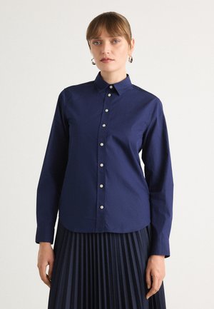 Navy blue button-up shirt with a collar, long sleeves, and a curved hem. Features silver buttons and smooth, structured fabric.