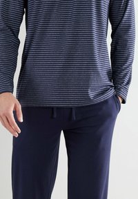 Navy long-sleeve top with thin horizontal stripes, paired with dark navy pants featuring a drawstring waist. Fabric appears soft and smooth.