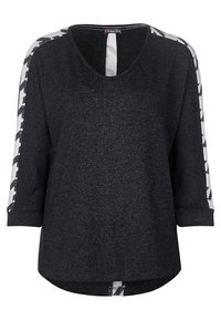 Svart långärmad topp med vita band som har svarta geometriska mönster längs ärmarna och en sprunddetalj på ryggen.