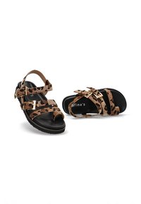 Sandalias negras para ni�ños con correas de estampado de leopardo marrón y negro y hebillas doradas, una sandalia de pie y la otra acostada de lado.