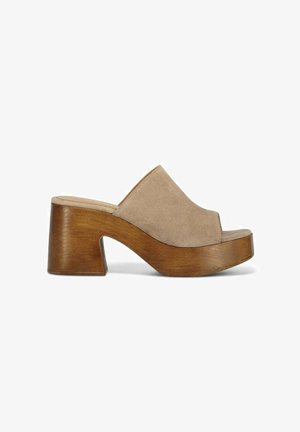 Beige suède open-toe mule met een gebogen houten chunky hak en platform, met een gladde textuur en een elegant ontwerp.