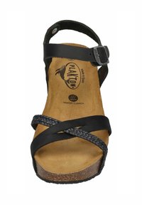 Black sandal featuring braided straps, an adjustable buckle, cork midsole, and memory cushion insole. Flat sole with textured surface.