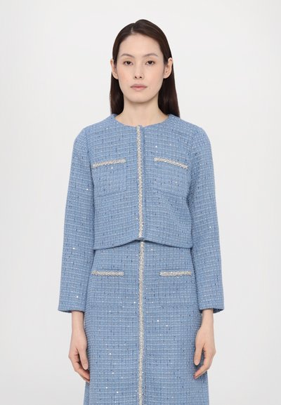 Giacca di tweed testurizzato blu chiaro con design cropped, tasche frontali e accenti argentati lungo la cerniera e i bordi delle tasche.