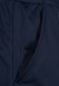 Navyblaues Gewebe mit glatter Textur, ausgestattet mit einer Seitentasche und einem elastischen Bund. Das Material wirkt leicht und atmungsaktiv.