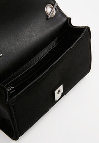 Black rectangular clutch bag with silver turn-lock closure and interior zippered pocket, open on a white background.