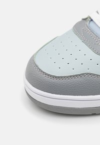 Sneaker z zaokrąglonym czubkiem, z jasnoniebieską i szaro skórzaną cholewką, perforowanymi detalami i białą gumową podeszwą.