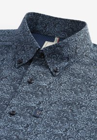 Camicia a fantasia floreale blu con bottoni scuri, colletto strutturato e fodera interna a pois in contrasto. Etichetta visibile vicino all'orlo.