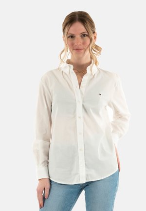Camicia bianca con bottoni realizzata in un tessuto leggero, con colletto classico, maniche lunghe e un piccolo logo sul petto.