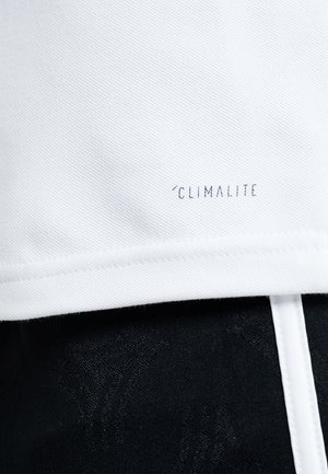 Witte stof met tekst "Climalite" dicht bij de rand boven zwarte stof met een subtiel gestructureerd patroon en een witte verticale streep.