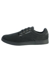 Zapatilla negra con parte superior de tela suave, puntera redondeada, diseño de cordones y acento con logo en el costado. Cuenta con una suela de goma gruesa.