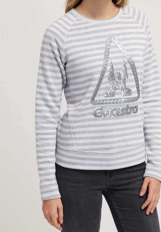 Sweat-shirt rayé gris et blanc avec un col rond et des manches raglan longues. Présente un logo graphique argenté sur le devant.