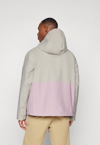 Leichte Kapuzenjacke mit einem zweifarbigen Design: hellgrauer Oberteil und sanft rosa Unterteil. Glattes Material mit lässiger Passform und verstellbarer Kapuze.