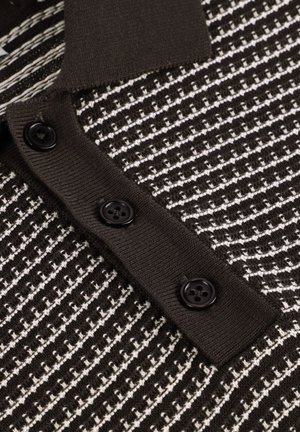 Schwarz-weißer Strickpullover mit strukturiertem Muster, ausgestattet mit einer gerippten Knopfleiste mit drei schwarzen Knöpfen.