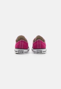 Ružičaste platnene tenisice s bijelim gumama, s Converse brendom na peti i kontrastnim bijelim šavovima. Niska verzija.