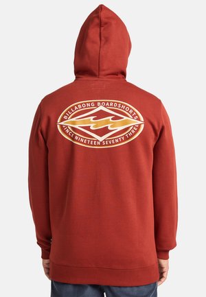 Roestkleurige hoodie met een groot, cirkelvormig Billabong-logo op de achterkant in wit en goud. Voorzien van een trekkoordcapuchon en ribgebreide manchetten.
