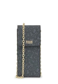 Bolso negro texturizado con cadena dorada y solapa plegable, que presenta el logo "TOUS" en dorado en la parte frontal.