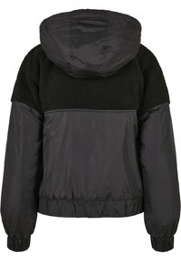 Chaqueta negra con capucha, que presenta una sección superior texturizada y una sección inferior lisa. Puños y cintura elásticos para un ajuste ceñido.
