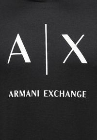 Μαύρο βαμβακερό t-shirt με έντονο λευκό κείμενο: «A|X» πάνω και «ARMANI EXCHANGE» κάτω σε καθαρή, μοντέρνα γραμματοσειρά.
