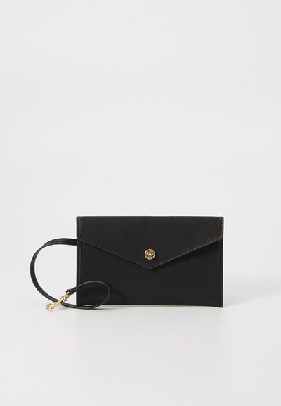 Porte-monnaie en tissu noir avec fermeture à pression dorée, de forme enveloppe slim et avec une sangle de poignet attachée. A une texture lisse et un design minimaliste.