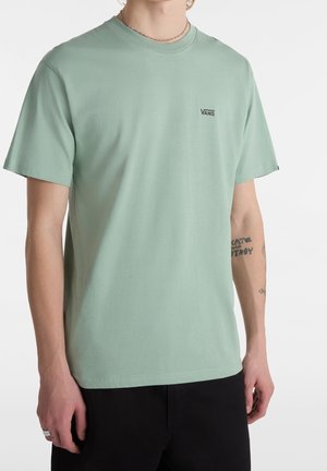 T-shirt en coton vert menthe à manches courtes avec un col rond, comportant un petit logo Vans noir sur la poitrine et une coupe décontractée.
