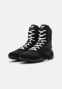 Schwarze High-Top-Schuhe aus Mesh-Textil, mit weißen Schnürsenkeln, einer strukturierten Sohle und einem markanten Logo an der Seite.