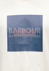 Biały bawełniany t-shirt z dużym kwadratowym nadrukiem w kolorze granatowym, z napisem "BARBOUR" na czerwono oraz "INTERNATIONAL" na biało.